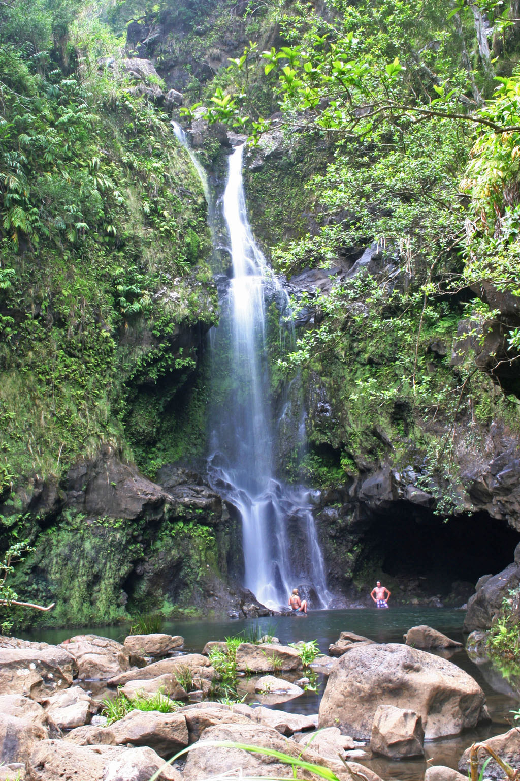 A couple enjoy sitting under the larger falls at Waikamoi